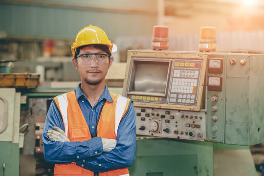 Steel factory staff worker portrait Asian man work in a heavy industrial machine with safety engineer uniform.