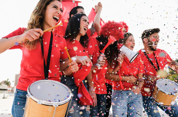 Red sport fans screaming while supporting their team out of the stadium - Soft focus on left girl...