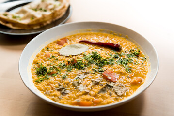 Traditional indian dal homemade. Traditional Indian soup lentils. Indian Dhal spicy curry in bowl with coriander and spices on wooden table with roti.