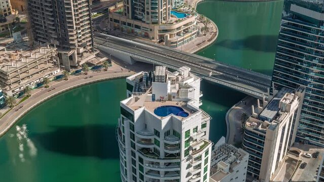 Dubai Marina waterfront and city promenade timelapse from above. Aerial view to skyscrapers along the canals. Towers rooftop with swimming pool