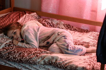 A little girl is lying in pajamas on the bed before going to bed.