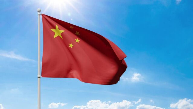 Red China Flag with golden stars flutters in the wind against a blue sunny sky