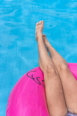 Beautiful woman legs sunbathing swimming pool.