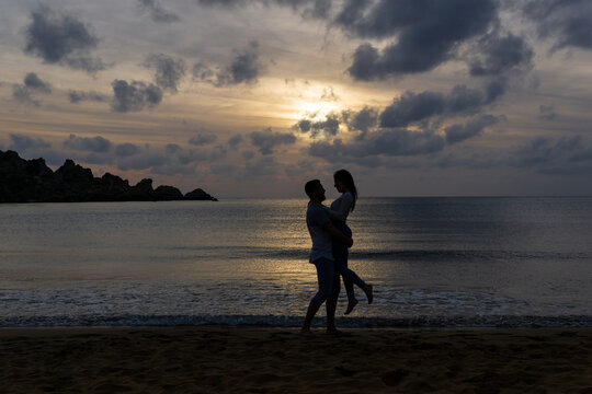 Young couple in love embracing on the beach with the sunset in the background.