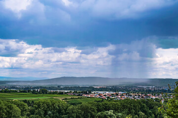 View over fields and forest towards Bretzenheim/Germany, which lies under a rain cloud