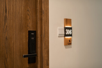 Closeup of wooden door with electronic key and room number in hotel - 516947905