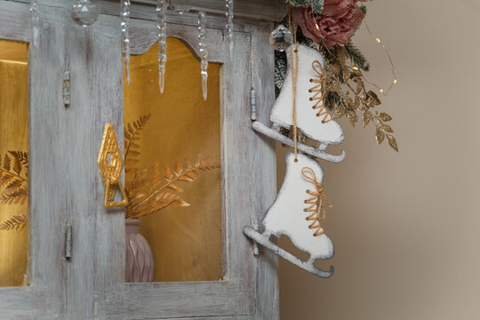 Wooden skates toy hanging on cupboard decorated with fir branches, icycles and snowy roses. merry Christmas decorated elements