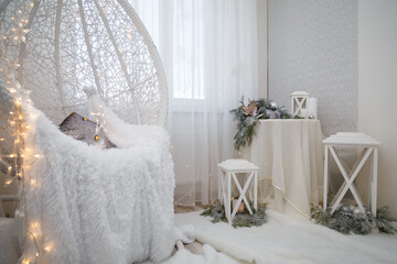 Beautiful white lace cocoon chair with plaid and cushion, golden garland lights in room decorated...