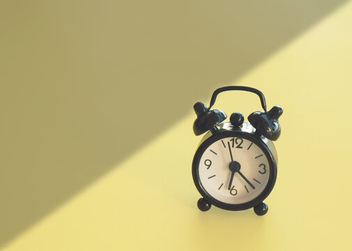 Retro alarm clok between night and day on a yellow background