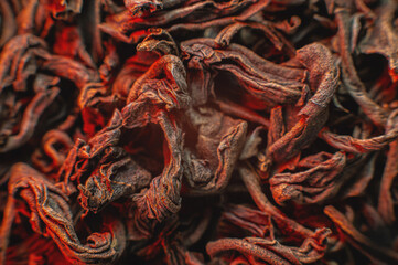 Dry black tea leaves close up. Macro background of tea production on a red light