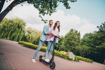 Photo of shiny funny young wife husband dressed pastel shirts driving kick bike enjoying sunshine...