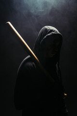 Silhouette of bandit holding baseball bat on black background with smoke