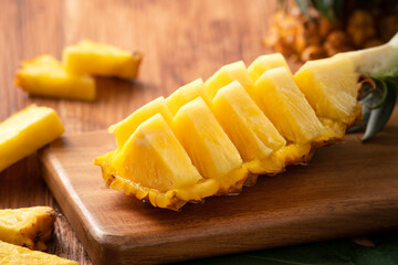 Fresh cut pineapple on a tray over dark wooden table background.