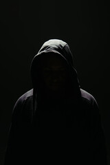 Silhouette of hooligan in hood standing in lighting isolated on black - obrazy, fototapety, plakaty