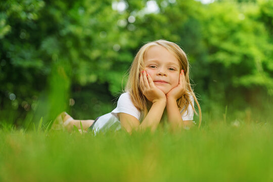 Portrait of a little girl who poses for a photo in the garden in summer.