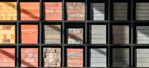 Stacks of various bricks on shelves. Examples of building materials - obrazy, fototapety, plakaty