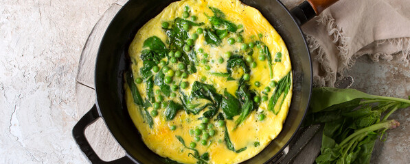 pan with scrambled eggs with spinach and green peas on the table