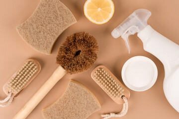 Obraz na płótnie Canvas Home cleaning bundle with natural products for green household over light brown background. Bamboo brushes, organic dishcloth, lemon, baking soda, citric acid, spray bottle. Mockup, flat lay style