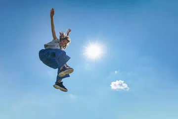Tuinposter Outdoor photo of young caucasian teenager jump with blue sky background. © Heorshe