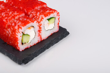close-up, on a white table, Japanese rolls with shrimp, cucumber and caviar of flying fish, there is a place for the inscription