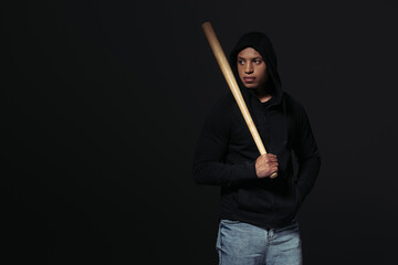 African american hooligan with baseball bat looking away isolated on black