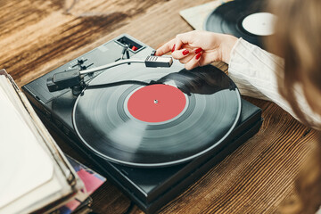 Young woman listening to music from vinyl record player. Playing music on turntable player. Female...