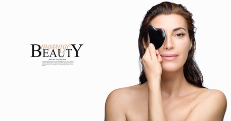 Beauty skincare concept with a gorgeous brunette woman covering one eye with a Gua sha tool