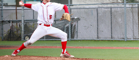 High school baseball pitcher in full wind up pitching during a game - obrazy, fototapety, plakaty