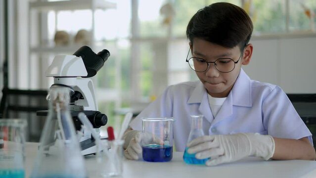 Asian boy researches blue liquid in chemistry lesson at laboratory