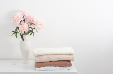 pink peonies in vase and female clothes in white room