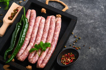 Raw sausages. Bratwurst or sausages with ingredients on cutting board with spices on a stone...
