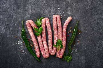 Raw sausages. Bratwurst or sausages with ingredients on cutting board with spices on a stone...