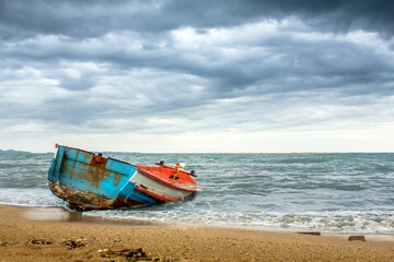 Abandoned ship on the seashore and the lines of the cloudy dark sky