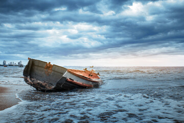 Abandoned ship on the seashore and the lines of the cloudy dark sky