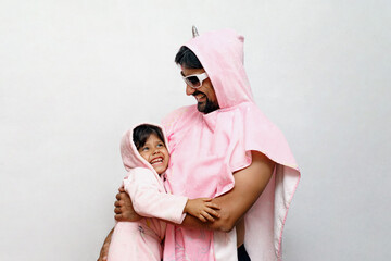 Dad in a pink poncho unicorn with his daughter, family relationships, fatherhood