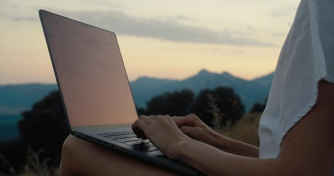 Closeup freelancer woman working with laptop computer outdoors at sunset. Creative freelance girl work remote from office on summer vacation with mountain view. Hands closeup type tex, email or code. 