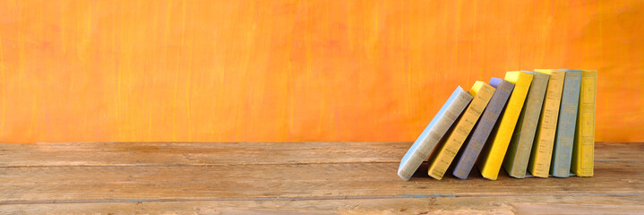 row of books on orange background, reading, education, education concept,  panoramic with large...