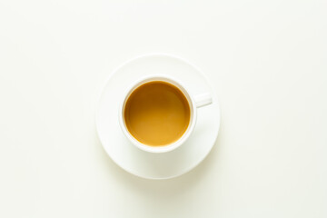 white cup of coffee with cream top view on white background