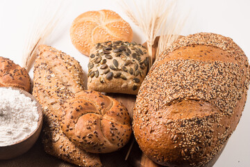 Assortment of baked bread with seeds on a white table background. Bakery. Food security concept.