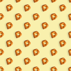 Seamless pattern of twisted baked rolls on a light yellow background