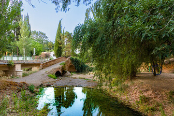 Paisaje de puente romano antiguo sobre un r&iacute;o reflejando el horizonte y paisaje verde de viaje en Riofr&iacute;o Granada