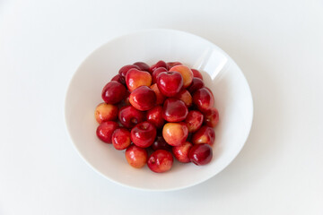 Ripe fresh cherries in a white plate on a white background. Close-up. Healthy food. Vegan breakfast.