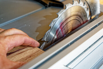 closeup of electrical saw table with blade that almost cut humand hand and fingers