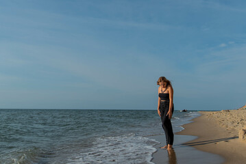 Woman wearing black dress walking on beach. See view