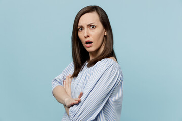 Obraz premium Side view young sad irritated annoyed indignant woman she 20s wears casual blouse hold hands crossed folded look camera isolated on pastel plain light blue background studio. People lifestyle concept.