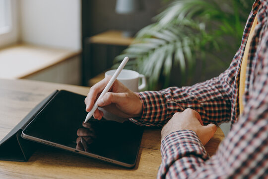 Cropped close up man he wearing shirt graphic designer hold work use write draw stylus pc pen sit alone at table in coffee shop cafe relax rest in free time. Freelance mobile office business concept.