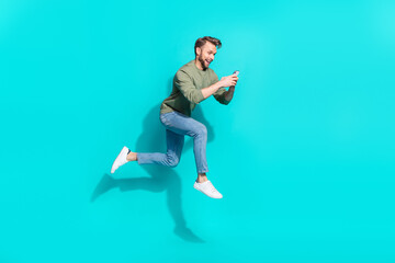 Fototapeta na wymiar Full length profile photo of funny nice blogger man jump hold telephone run wear pullover isolated blue color background
