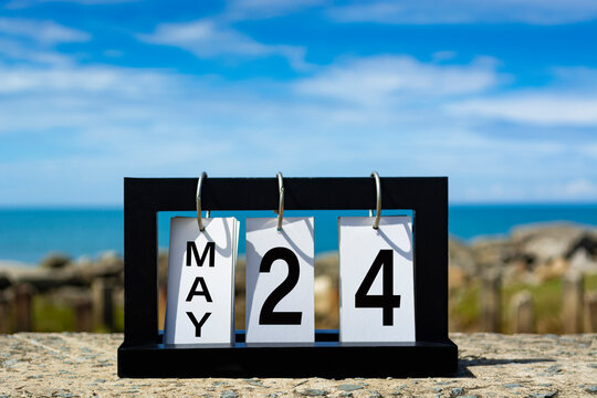 May 24 calendar date text on wooden frame with blurred background of ocean.