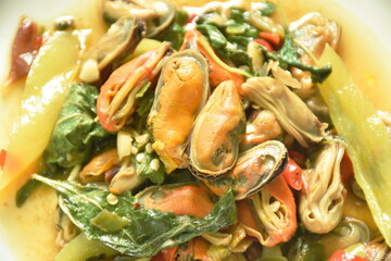 spicy stir fried mussel with slice onion and basil leaf on plate