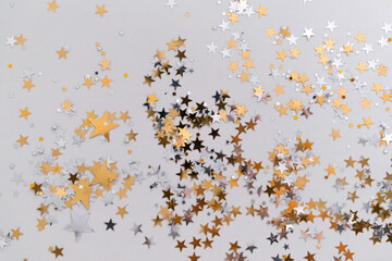 golden confetti stars on grey background top view